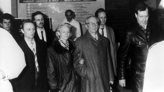 Der ehemalige Staats- und Parteichef der DDR, Erich Honecker (m) und seine Ehefrau Margot verlassen am frühen Morgen des 29. Januar 1990 das Krankenhaus Charité in Ost-Berlin. Honecker wurde noch am Krankenhaustor vorläufig festgenommen und in die Untersuchungshaftanstalt Berlin-Rummelsburg gebracht. © picture-alliance/ dpa | dpa 