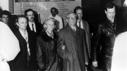 Der ehemalige Staats- und Parteichef der DDR, Erich Honecker (m) und seine Ehefrau Margot verlassen am frühen Morgen des 29. Januar 1990 das Krankenhaus Charité in Ost-Berlin. Honecker wurde noch am Krankenhaustor vorläufig festgenommen und in die Untersuchungshaftanstalt Berlin-Rummelsburg gebracht. © picture-alliance/ dpa | dpa 