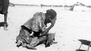 Ein hoffnungsloser Mann hockt in der Sahelzone in Afrika in den 1970-er Jahren am Boden. © picture-alliance/ dpa | DB UN 