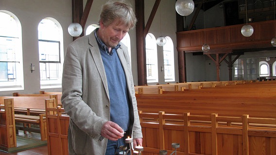 Pastor Jörg Schulze zündet in der Christuskirche auf Borkum Kerzen an. © NDR Foto: Carsten Valk