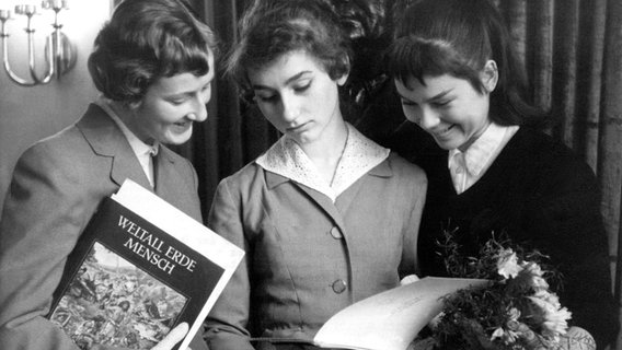 Drei Jugendliche mit einem Buch-Geschenk, Blumen und einer Urkunde,die sie anlässlich ihrer Jugendweihe 1958 bekommen haben. © picture-alliance / dpa | ADN Zühlsdorf 