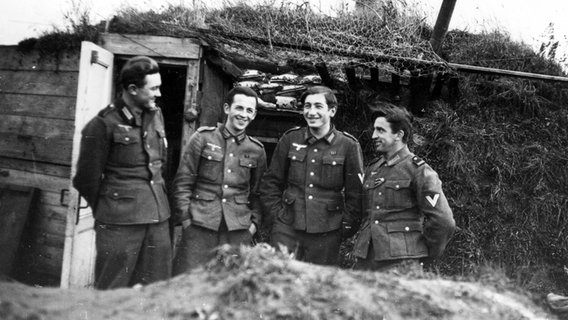 Vier Wehrmachtssoldaten posieren vor dem Eingang ihrer primitiven Unterkunft. © privat 