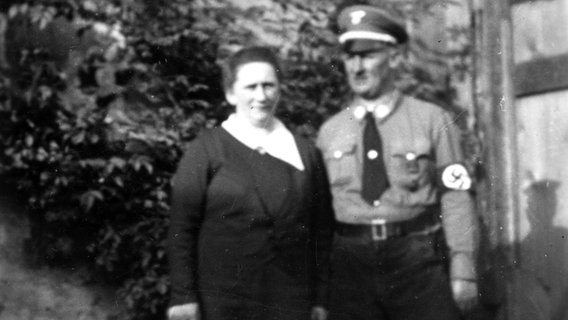 Walter Benthins Eltern posieren vor einem Busch; sein Vater trägt eine NSDAP-Parteiuniform. © privat 