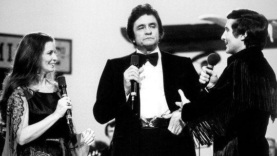 Moderator Freddy Quinn steht neben der US-Country-Legende Johnny Cash während einer Musikshow. © picture-alliance / dpa Foto: Dröse