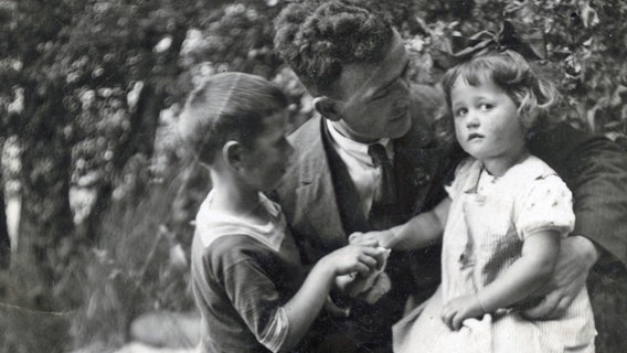 Gerda Gidl sitzt als Einjährige auf dem Knie ihres Vaters, daneben steht ihr Bruder. © privat 