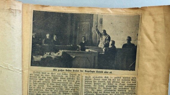 Abfotografierter historischer Zeitungsausschnitt mit einem Foto von Adolf Seefeld vor Gericht, auf dem der er seine Faust hebt. © Stadtarchiv Schwerin 
