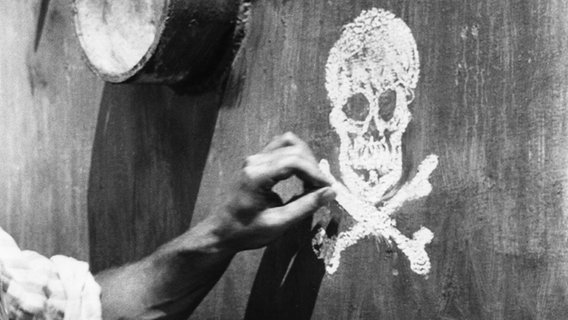 Mit Kreide wird ein Totenkopf gemalt: Szene aus dem Film "Das Totenschiff" (BRD/MEX 1959) (Ausschnitt) - nach dem Roman von B. Traven © picture-alliance 