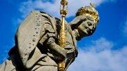 Eine mit goldener Krone und Zepter verzierte Statue von "Kaiserin Kunigunde von Luxemburg" steht 2012 auf der Unteren Brücke in Bamberg (Bayern) vor blauem Himmel. © picture alliance / dpa Foto: David Ebener