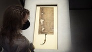 Eine Mitarbeiterin des Britischen Museums in London betrachtet ein Blatt der Magna Carta, das Teil der Ausstellung "Thomas Becket: murder and the making of a saint" im Jahr 2021 ist. © picture alliance / empics Foto: Victoria Jones