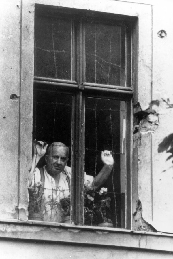 Ein Bewohner der Bernauer Straße blickt am 4. September 1961 aus seinem mit Stacheldraht geschlossenen Fenster in den Westen. © picture-alliance / akg-images Foto: akg-images