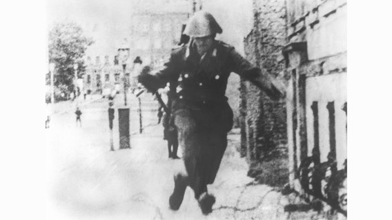Der 19-jährige Conrad Schumann flüchtet am 15. August 1961 mit einem Sprung über eine Stacheldrahtabsperrung vom sowjetischen Sektor in den Westteil Berlins. © picture-alliance / dpa Foto: UPI