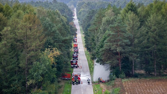Einsatzkräfte der Feuerwehr bewässern den Straßenrand nahe dem Moorbrand auf dem Bundeswehr-Testgelände im Emsland. © picture alliance | dpa Foto: Mohssen Assanimoghaddam