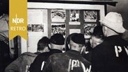 Kriegsgefangene des Zweiten Weltkriegs in einem britischen Gefangenenlager betrachten Bilder, die die Gräueltaten in deutschen Konzentrationslagern zeigen, Mai 1945. © IMAGO IMAGES / Photo12 