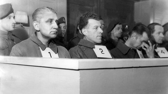 Neuengamme-Prozess am 29. April 1946  Curio-Haus in Hamburg: In der ersten Reihe sitzend (l-r): der ehemalige Lagerkommandant Max Pauly (1), sein Adjutant Karl Totzauer (2), der Lagerführer Anton Thumann (3) sowie der SS-Arzt Dr. Bruno Kitt (4). Ihnen wird vorgeworfen, mehr als 45.000 Insassen des Lagers ermordet zu haben. © picture alliance / dpa | DANA dpa 