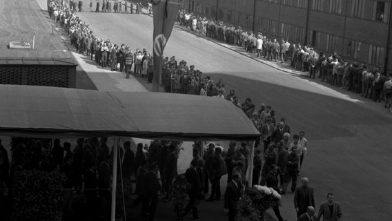 Tausende VW-Mitarbeiter stehen 1968 auf dem Werksgelände vor einer Versuchshalle Schlange, in der der Sarg des verstorbenen Vorsitzenden Heinrich Nordhoff aufgebahrt ist. © Volkswagen AG 