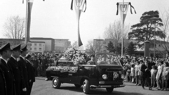 Menschen säumen 1968 eine Straße in Wolfsburg, als der Sarg des verstorbenen VW-Chefs Heinrich Nordhoff auf einem Pritschenwagen vorbeigefahren wird. © Volkswagen AG 