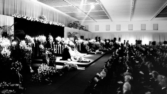 1.700 Gäste sitzen 1968 während einer Trauerfeier in einer Volkswagen-Halle vor dem Sarg des verstorbenen Vorsitzenden Heinrich Nordhoff. © Volkswagen AG 