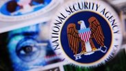 Illustration:  Durch eine Lupe ist das Logo des US-Geheimdienstes National Security Agency (NSA) auf einem Monitor zu sehen. © picture alliance / dpa Foto: Nicolas Armer