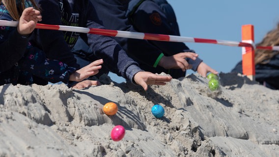 Kinder lassen bunte Eier eine Düne hinunter rollen. © picture-alliance / dpa Foto: Jannis Meyer