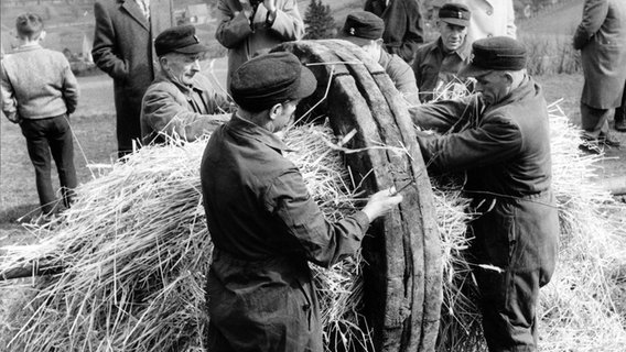 In den Tagen vor Ostern im April 1962 werden auf dem Osterberg in Lügde die Eichenräder für den traditionellen Osterräderlauf vorbereitet, das heißt mit Stroh ausgestopft. Am Osterabend rollen sie dann brennend ins Tal. © picture-alliance / dpa 