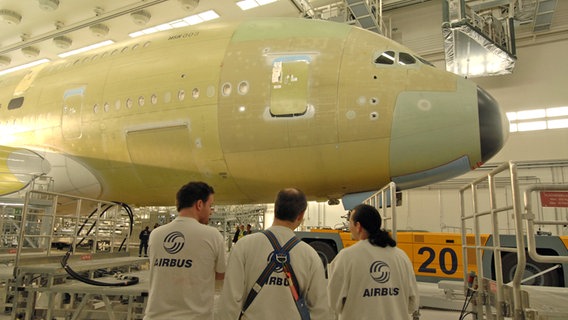 Airbus-Mitarbeiter stehen in der sogenannten Painthall vor einem unlackierten A380. © Airbus 2007 Foto: C. Brinkmann