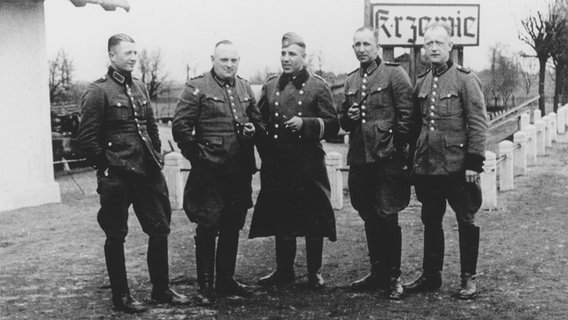 Gruppenbild von Mitgliedern des Polizeibataillons 101 Anfang der 1940er-Jahre vor einem Ortsschild von Krzewie (Polen) © United States Holocaust Memorial Museum, courtesy of Michael O'Hara 