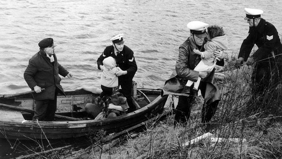 Freiwillige Helfer und Polizisten bringen am 17.02.1962 bei der Sturmflut in Hamburg Kleinkinder in Sicherheit. © dpa-Bildfunk Foto: Gerd Herold