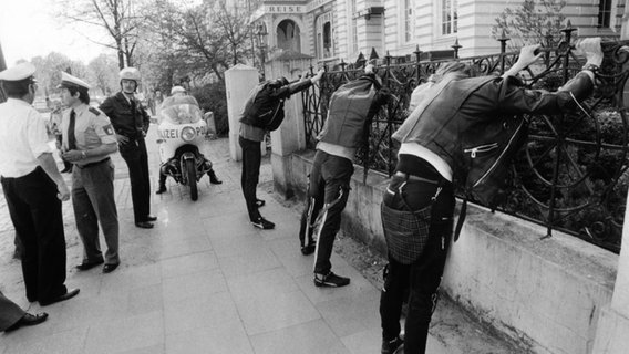 Männer stehen mit erhobenen Armen an einem Zaun. © Hamburg Journal 
