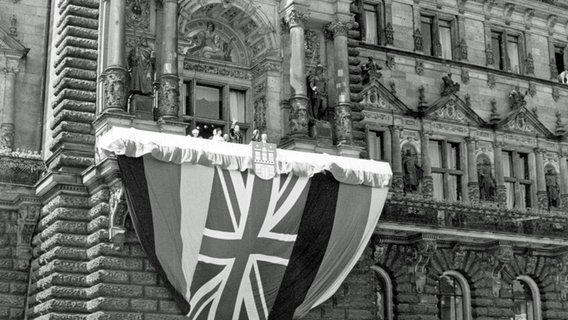 Königin Elizabeth II. und ihr Gatte Prinz Philip stehen am 28. Mai 1965 auf dem fahnengeschmückten Balkon des Hamburger Rathauses. © picture alliance / dpa 