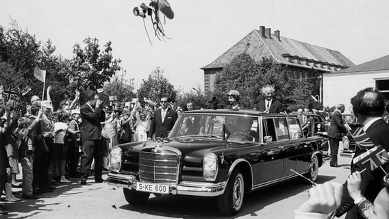 Königin Elizabeth II. und Hamburgs Erster Bürgermeister Paul Nevermann fahren am 28. Mai 1965 nach dem Besuch einer Volksschule in einer offenen Limousine durch Hamburg. © picture alliance / dpa 