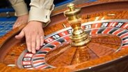 Hand an einem Roulette-Rad © Fotolia.com Foto: Denys Kurbatov