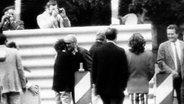 Der Ost-Berliner Anwalt Wolfgang Vogel (Mitte links) umarmt zur Begrüßung eine DDR-Bürgerin. Am alliierten Grenzübergang Glienicker Brücke in Berlin findet am 11.06.1985 der größte Agentenaustausch zwischen Ost und West seit 1945 statt. Vier in den USA verurteilte Agenten wurden gegen insgesamt 25 Mitarbeiter amerikanischer Nachrichtendienste ausgetauscht. Ein Fernsehteam der "Tagesschau" filmte den Austausch. (Screenshot) © picture alliance / ARD/Tagesschau Foto: ARD/Tagesschau