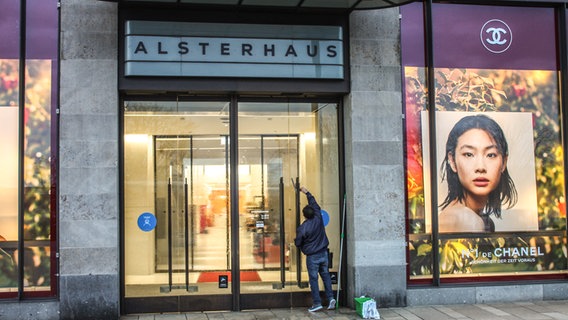 Ein Fensterputzer putzt die Eingangstür am Hamburger Alsterhaus. © NDR Foto: Daniel Sprenger