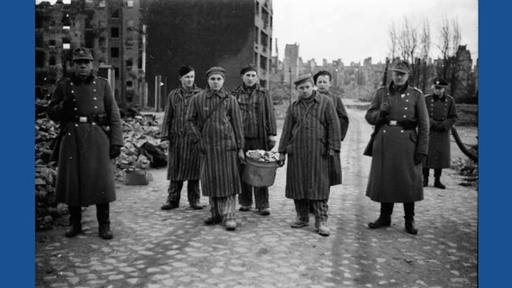 Polizeireservisten bewachen Häftlinge des KZ Neuengamme bei Aufräumarbeiten in Hamburg. © KRONOS Media GmbH, Sammlung Uwe Petersen, HHWW2-Rolle 48_20140624_0010 Foto: Andreas Werner (Polizeiangehöriger)