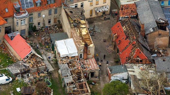 Am Tag nach dem schweren Tornado in der Kleinstadt Bützow (Mecklenburg-Vorpommern) räumen Anwohner, Helfer und Feuerwehrleute am 06.05.2015 Dachbalken und Ziegelsteine von zerstörten Häusern in der Altstadt. © picture alliance / dpa Foto: Jens Büttner