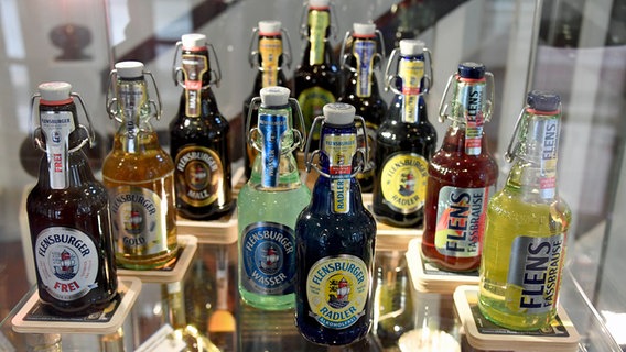 Verschiedene Bier-Produkte stehen in einer Vitrine der Flensburger Brauerei. © picture alliance/dpa Foto: Carsten Rehder