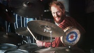 Der Schlagzeuger Ginger Baker spielt sein Instrument und lächelt in die Kamera. © dpa - Bildarchiv Foto: Otto