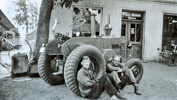 Zwei Männer sitzen vor dem ehemaligen "Pötte un Pannen Markt", direkt an der alten Schmiede. Aufnahme von circa 1935.  
