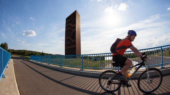 Ein Radfahrer fährt an einem Aussichtstturm im Lausitzer Seenland vorbei Ein Radfahrer fährt an einem Aussichtstturm im Lausitzer Seenland vorbei © dpa / Picture Alliance Foto: Andreas Franke