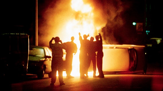 Menschen vor einem brennenden Auto bei den Ausschreitungen in Rostock-Lichtenhagen im August 1992 © Reuters/Corbis Foto: Lutz Schmidt