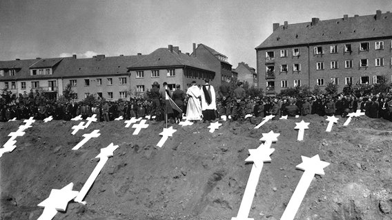 Die Markierungen beziehen sich auf in Ludwigslust gefundene Gräber von 80 Opfern der Nazis. Die gesamte Bevölkerung von Schwerin wurde von der Militärregierung angewiesen, an Beerdigungsritualen teilzunehmen, die von Seelsorgern der US-Armee durchgeführt wurden. (08.05.1945) © picture-alliance / DoD Foto: A. Drummond