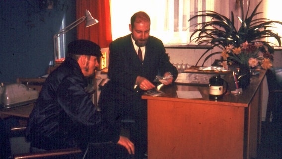 Ein Seemann (links) gibt im Seemannsheim Krayenkamp seine Heuer in Verwahrung.  