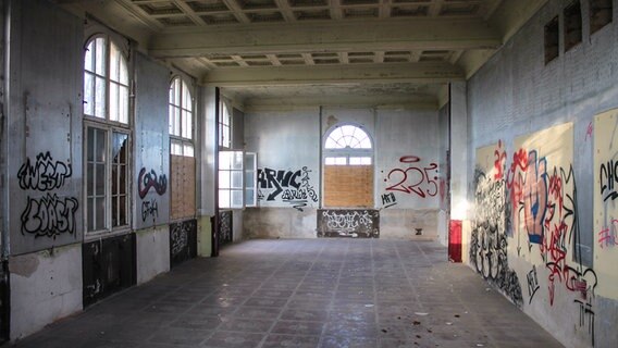 Der frühere Speisesaal in der Villa Baltic in Kühlungsborn ist mit Graffiti beschmiert, bis auf eines sind alle Fenster vernagelt. © NDR Foto: Daniel Sprenger