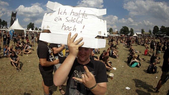 Ein Metalfan hält am 02.08.2014 in Wacken (Schleswig-Holstein) vor den Bühnen eine Schild mit der Aufschrift "Ich halte ein Schild hoch!" in der Hand. © picture alliance / dpa Foto: Axel Heimken