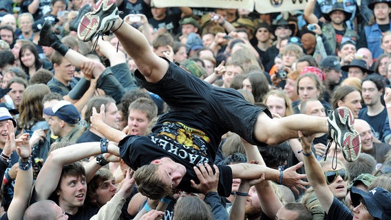 Fans amüsieren sich am 4. August 2010 beim Auftritt der "Wacken Fire Fighters". Die Band der freiwilligen Feuerwehr eröffnet traditionell inoffiziell das Heavy-Metal-Festival im schleswig-holsteinischen Wacken. © picture alliance / dpa Foto: Carsten Rehder