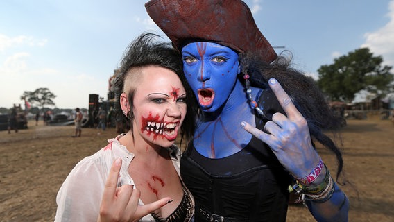 Verkleidete und geschminkte Besucher des Wacken Open-Air Festivals (WOA) zeigen am 1. August 2014 im schleswig-holsteinischen Wacken die "Pommesgabel". © picture alliance/dpa Foto: Axel Heimken