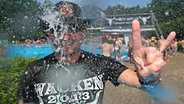 Wolfgang (52) aus Hessen zeigt am 01.08.2014 in Wacken (Schleswig-Holstein) im Schwimmbad unter einer Dusche die "Pommesgabel", den Gruß der Heavy-Metal Fans. © picture alliance / dpa Foto: Axel Heimken
