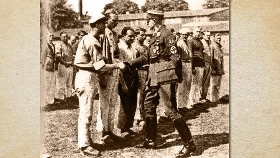 Der Hamburger Polizeisenator Alfred Richter (rechts) schüttelt im KZ Wittmoor einem Gefangenen die Hand. © Stadtarchiv Norderstedt 