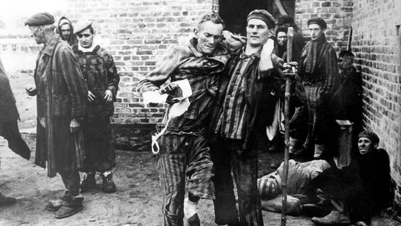 Ein Gefangener des Konzentrationslagers Wöbbelin wird nach der Befreiung am 02.05.1945 durch die 82. US-Luftlandedivision von einem Mithäftling zur ärztlichen Betreuung geführt. © dpa 