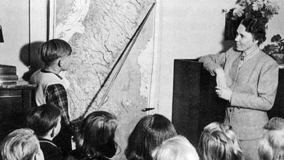 Eine Lehrerin beobachtet einen Jungen mit Zeigestock vor einer Landkarte © Schwedische Kirche in Hamburg 